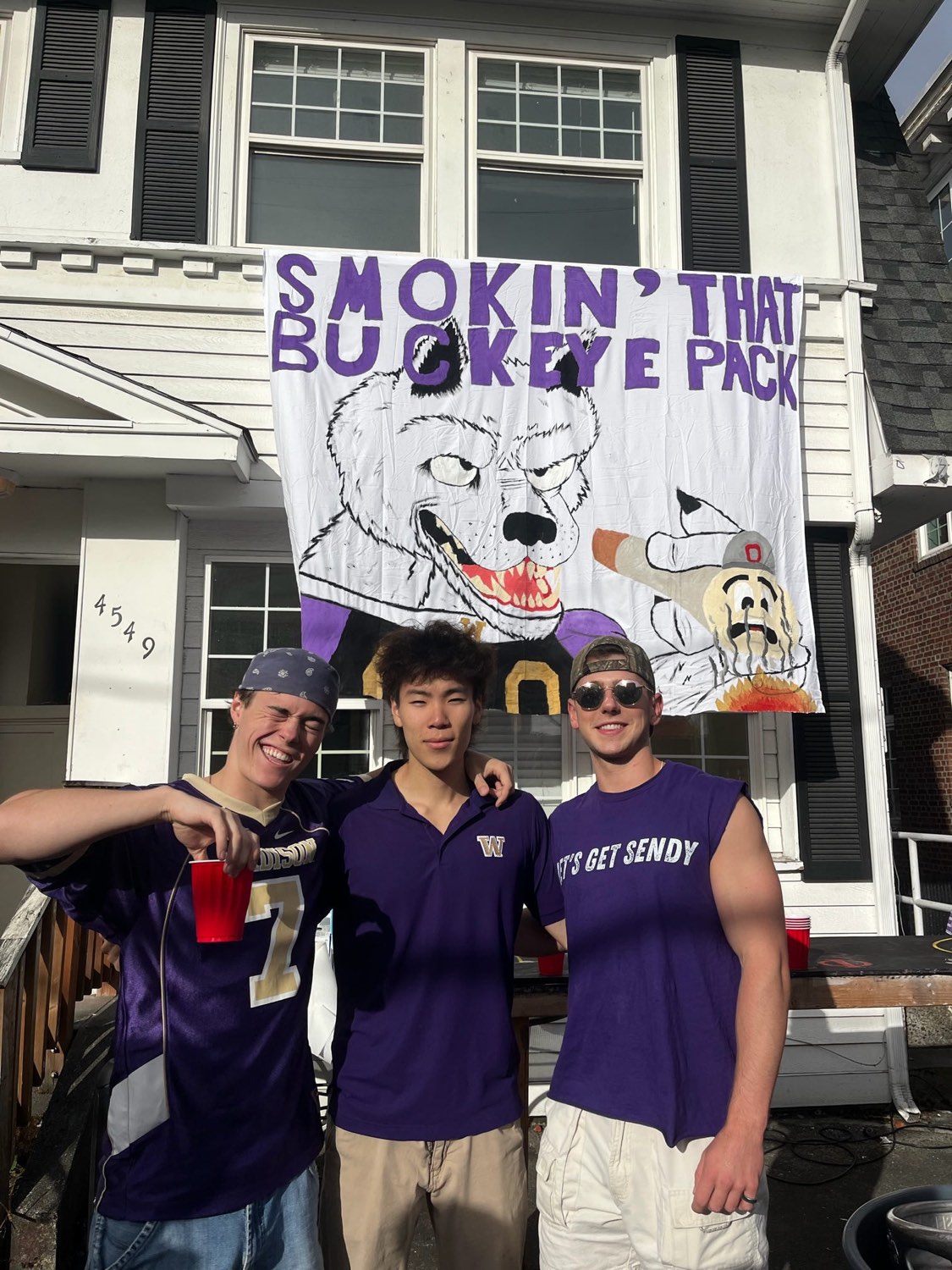 Brothers on game day in front of a hand-painted Husky banner