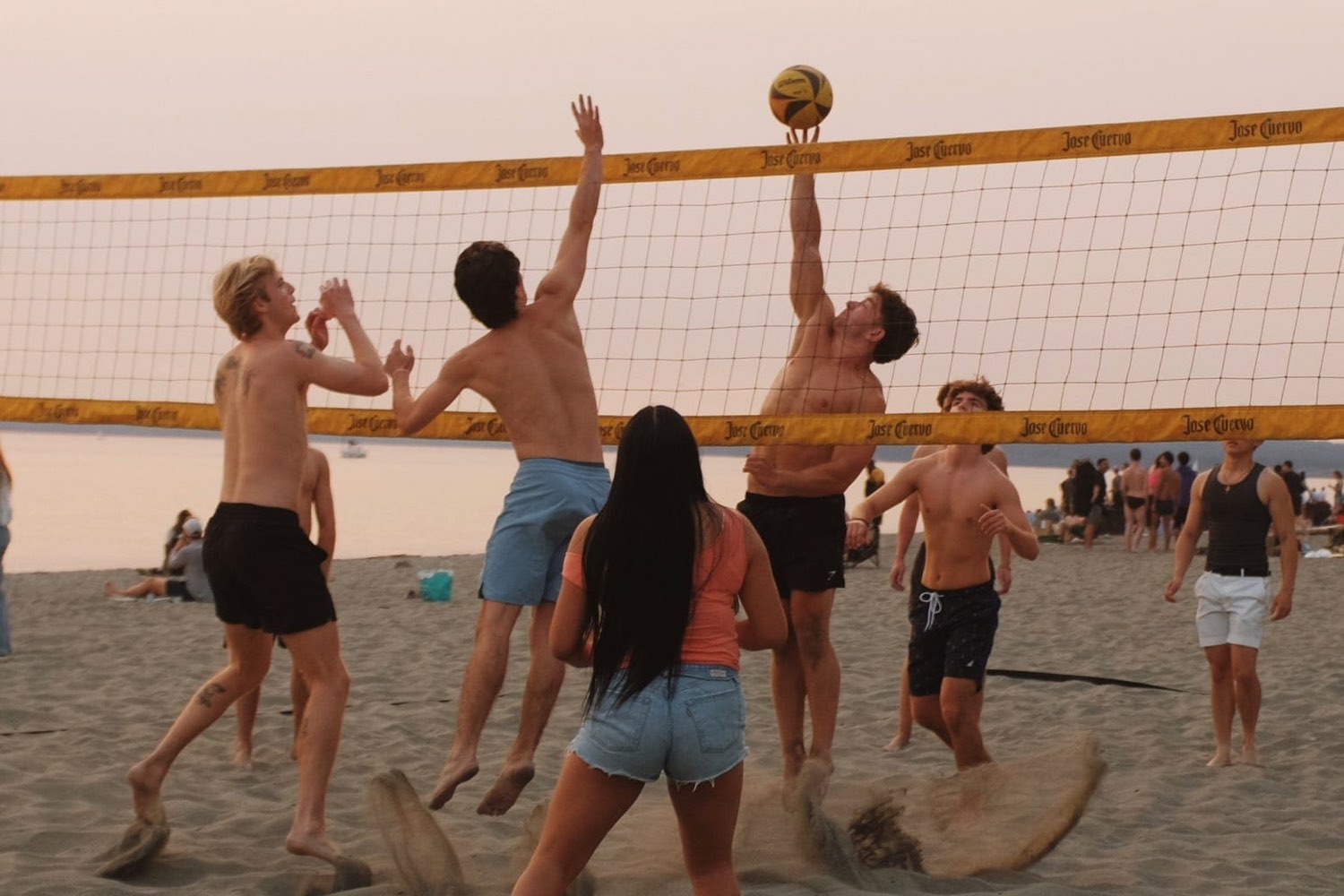 Brothers playing beach volleyball at sunset
